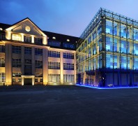 Außenansicht des Zentrums für Kunst und Medientechnologie Karlsruhe bei Nacht. Links befindet sich der Altbau und rechts der bunt beleuchtete Glasneubau.