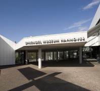 Außenansicht des Eingangsbereiches des Sprengel Museums in Hannover. Vorwiegend ist eine weiße Fassade und einige Säulen erkennbar